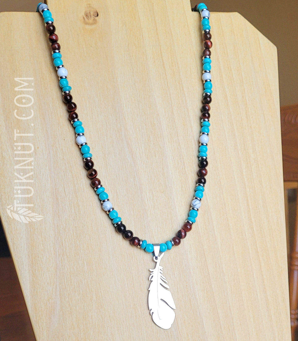 Collier d'inspiration autochtone (monté sur fil en acier inoxydable) avec oeil de tigre rouge, turquoise, howlite, billes séparatrices et pendentif (plume) en acier inoxydable (couleurs : brun-rouge, turquoise, blanc et argent) TUKNUT