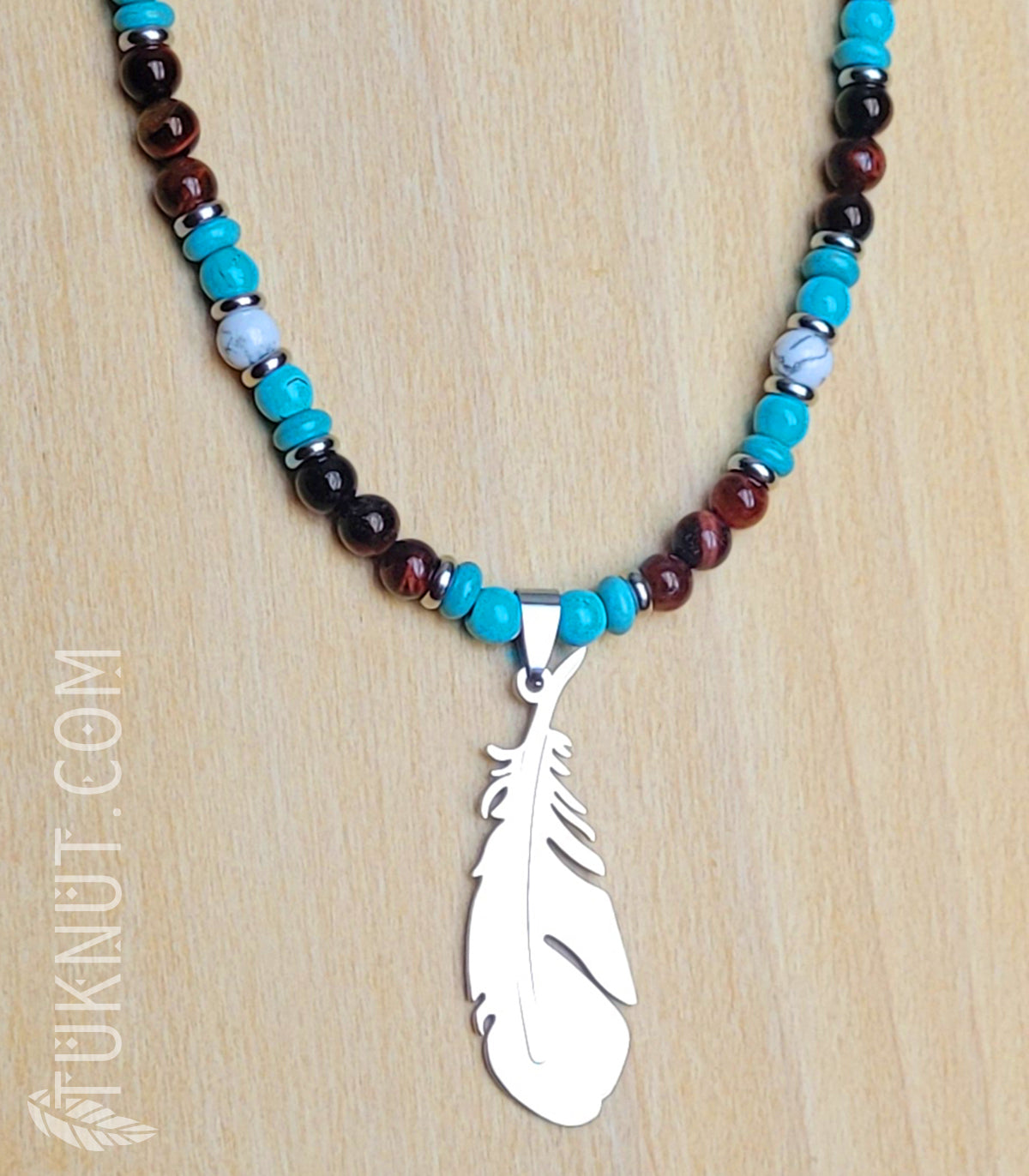 Collier d'inspiration autochtone (monté sur fil en acier inoxydable) avec oeil de tigre rouge, turquoise, howlite, billes séparatrices et pendentif (plume) en acier inoxydable (couleurs : brun-rouge, turquoise, blanc et argent) TUKNUT